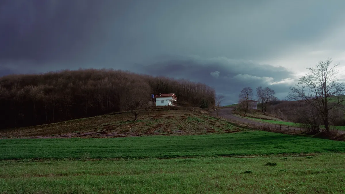 House on a sloped hillside under dark clouds