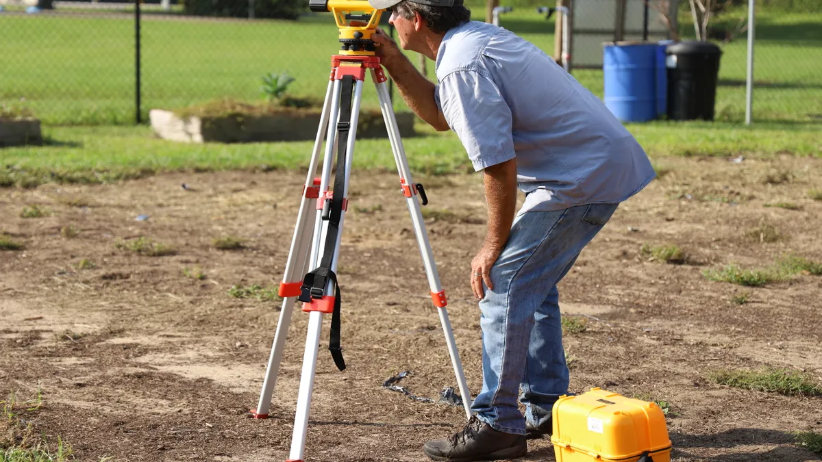 person using a survey tripod instrument outdoors