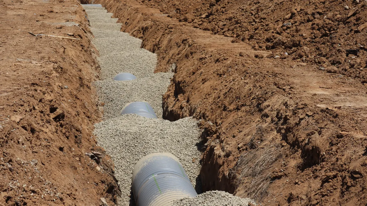Trenched yard with gravel and drainage pipes