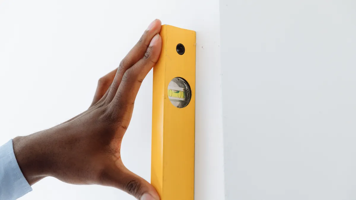 hand using a spirit level against a wall